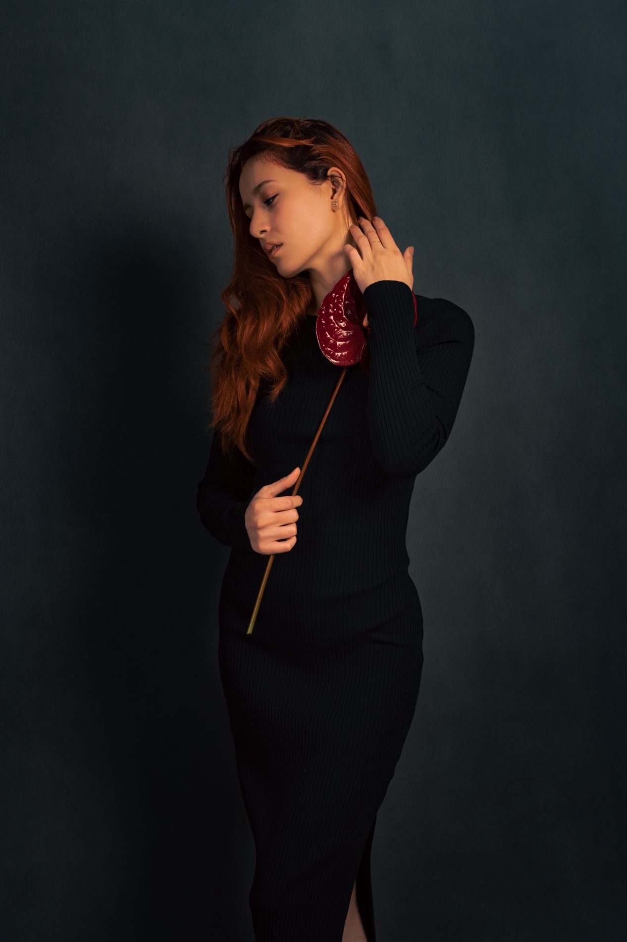 Low-key fashion portrait with blue flower and red hair